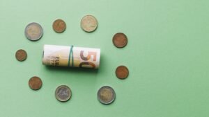 Billete de euro enrollado junto a varias monedas