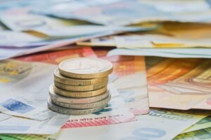 Monedas de euro apiladas sobre billetes